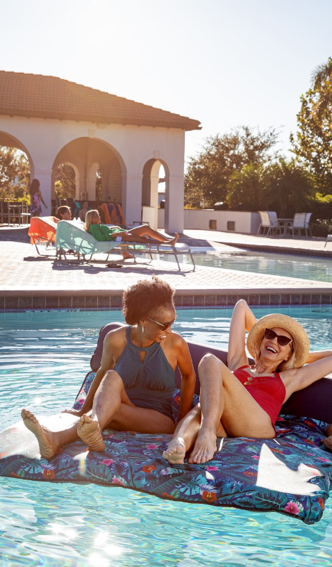 Two women relaxing on a float in the resort-style community pool